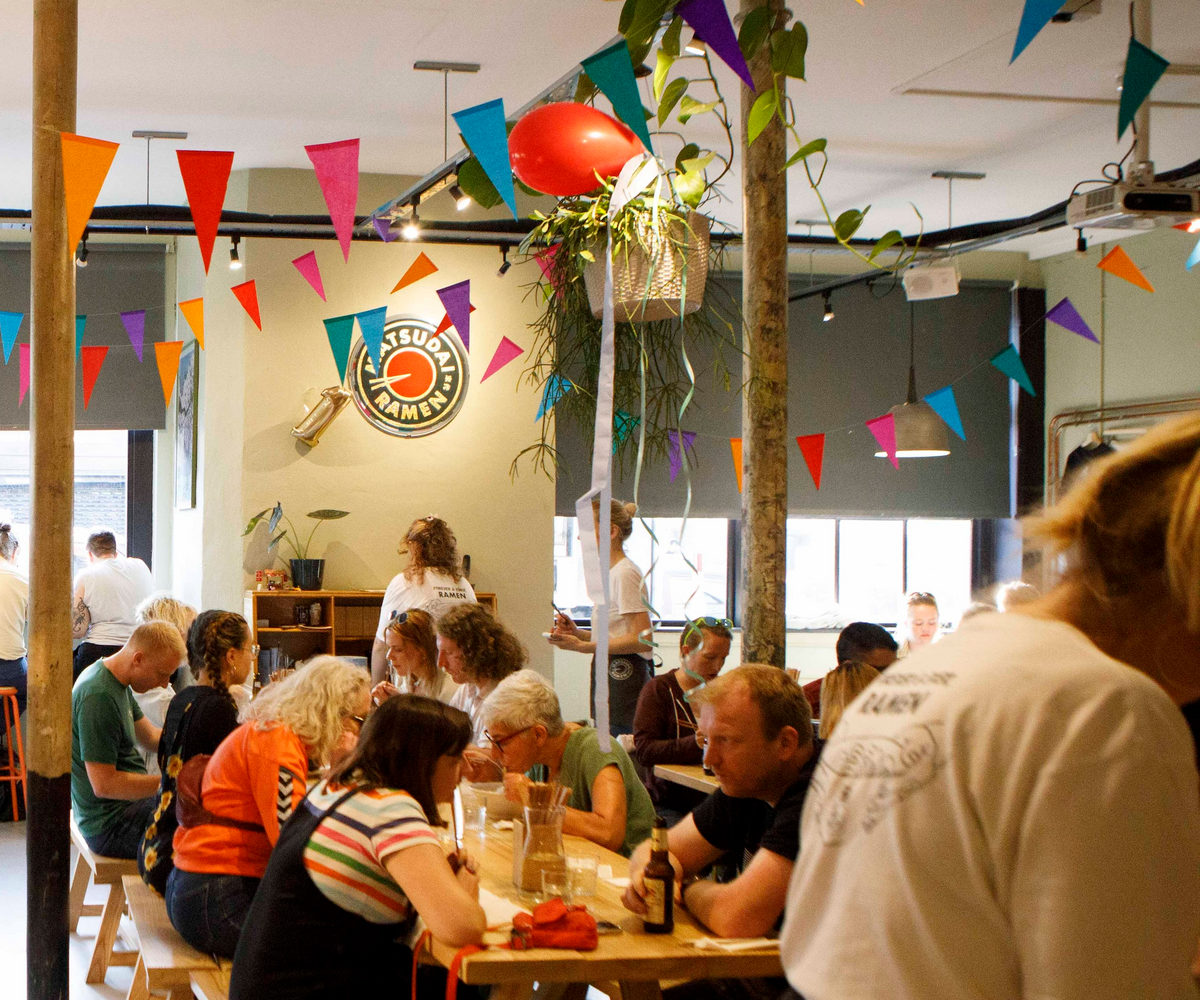 the restaurant full of people, bunting up, the matsudai logo on the wall